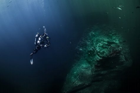 Scuba diving in deep sea with rocks, free public domain CC0 photo.
